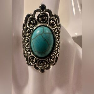 Turquoise-colored stone set in ornate
silver-colored metal band rose motifs.
SZ8